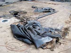  A poorly bonded hot-applied rubberized asphalt waterproofing membrane is being removed from a concrete plaza deck.