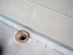 This is a poor deck drain location, as it is next to a wall within a perimeter flashing detail.