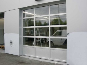 This is a different style of an aluminium overhead door where the bottom panels are insulated and have a ‘kick-proof’ design. The bottom section absorbs the impact of the door closing, reducing any jarring of the glazing in the above panels.