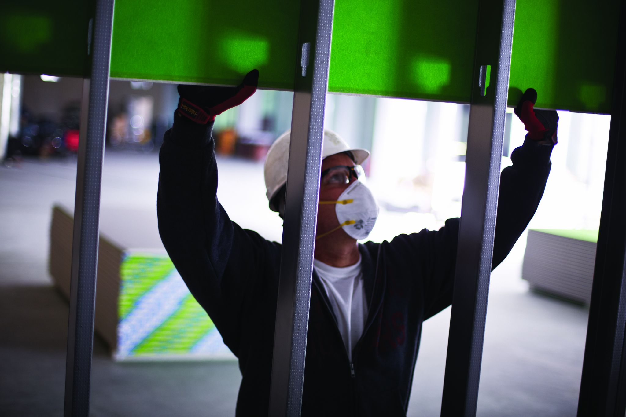 This shows a worker installing glass-mat water and mould-resistant interior gypsum panels during pre-dry-in construction before closing up the structure. Photo courtesy USG