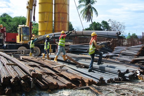 SELANGOR, MALAYSIA - APRIL 15, 2015: Group of construction workers lifting bundle of reinforcement bar using crane at the construction site.