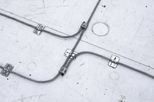 Bends in conductors must have a large radius to prevent high voltage current from jumping off the cable and seeking another path to ground. The adhesive used to secure fittings to the single-ply roof must be acceptable to the membrane manufacturer. Photo courtesy Boston Lightning Rod Company 