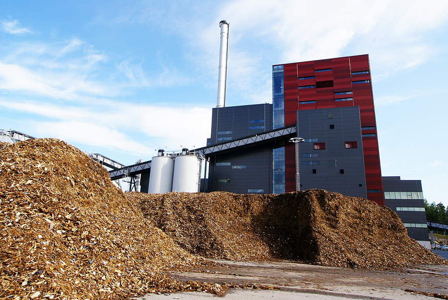 bio power plant with storage of wooden fuel (biomass) against blue sky