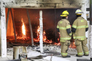 Firefighters from the National Institute of Standards and Technology (NIST) look over the end of a controlled test to study the impact of fire on cross-laminated timber (CLT) buildings. CLT has been identified in a new NIST report as needing more flammability research. Photo courtesy NIST