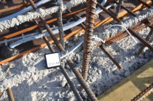 A wireless concrete temperature sensor installed on rebar prior to pour.