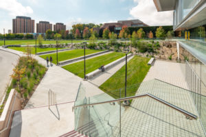 A natural amphitheatre was created at York University (Toronto), extending the indoor realm into the environment with grass slopes, natural stone seating, and an escarpment wall. Images courtesy FORREC