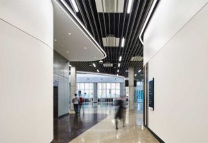 With disparate spaces designed for vastly different types of research, the Northern Alberta Institute of Technology's (NAIT's) Productivity and Innovation Centre varied greatly in acoustic performance demands. In the building’s B wing, aluminum baffles control acoustics while helping to achieve the ‘NAIT’ esthetic by allowing the ceiling’s dark texture to show through.