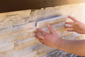 Installing stone veneers requires multiple layers of mortar, a scratch coat, metal lath, and two layers of weather-resistive barrier (WRB) in addition to weep screens and screeds for adequate moisture management. Photo © Shutterstock/Ronstik