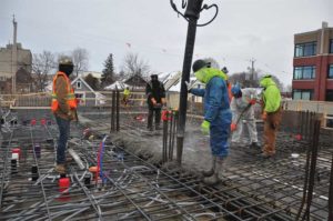 Construction workers pouring and levelling concrete for a mass project in the winter.