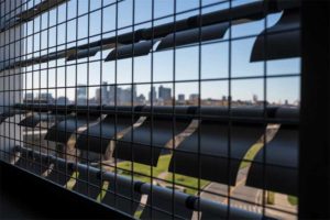 For the West Garage kinetic façade system for the Boston Logan International Airport, Mass., more than 48,000 square flapper panels are set within 353 extruded aluminum framing support assemblies spanning eight stories high  x 88 m (290 ft) wide. Various shapes, material thickness, and finishes were tested, resulting in the curved aluminum flapper elements that reflect light and move in response to wind currents. 