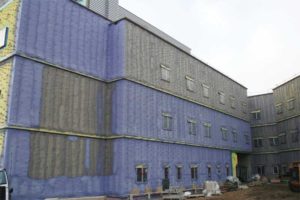 Spray foam insulation applied on glass mat gypsum board as continuous cavity wall insulation on the exterior of a hospital.