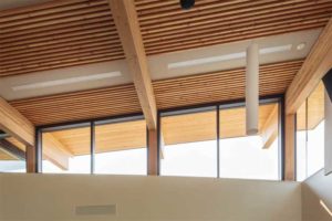 Dowel-laminated timber (DLT) panels have alternate 2x4 and 2x6 members creating a corrugated soffit. The 600-mm (24-in.) gap between panels accommodates lighting and is concealed with an acoustic panel. Photo © Dave Best