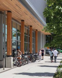 The main entrance canopy features cross-laminated timber (CLT) panels supported by glulam posts, lifted above the sidewalk on concrete pedestals.