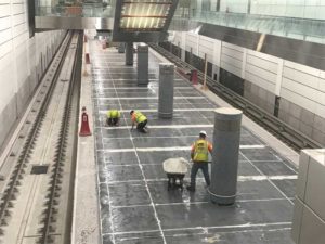 Workers constructing a subway platform floor.