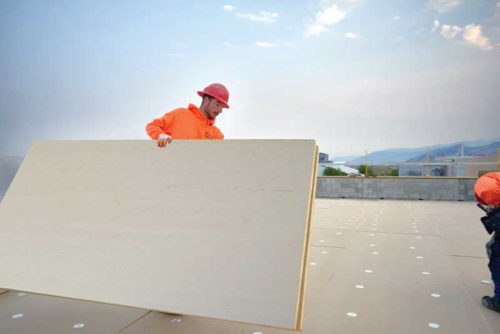 A worker applying polyiso boards to a roof. These boards enable building teams to achieve the desired thermal performance.