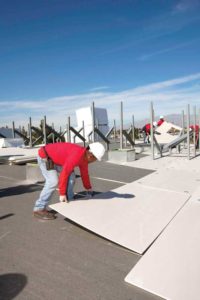 Man installing energy-saving, code-congruent roof insulation above the deck in an existing building.