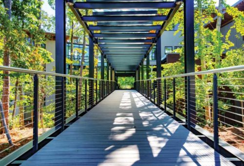 Cable railings installed on the edges of a pedestrian bridge, allow for natural light to filter in.