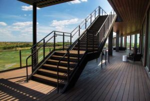 A deck and a staircase leading up from it feature cable railings.