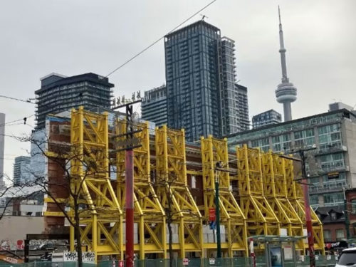 yellow retention towers used for construction with the CN Tower in the background