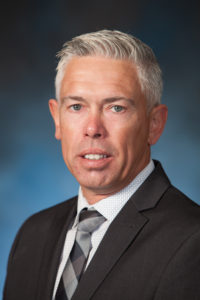 headshot of a man in a suit and white hair