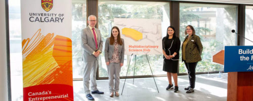 four people standing in formals in front of a 'University of Calgary' banner