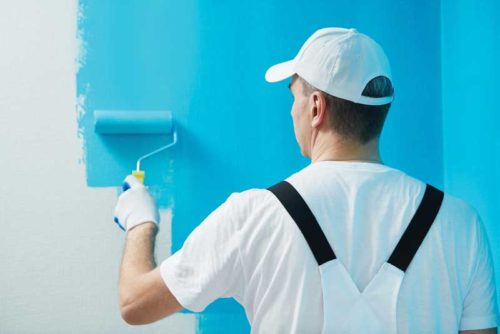 painter with a paint roller painting blue