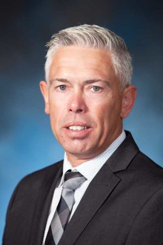 headshot of a man in front of a blue backdrop