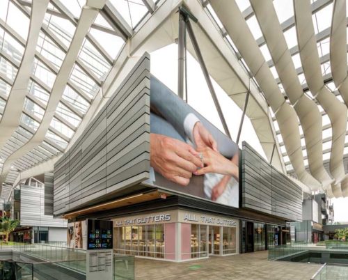 billboard inside a mall with the image of a man putting a ring on a woman