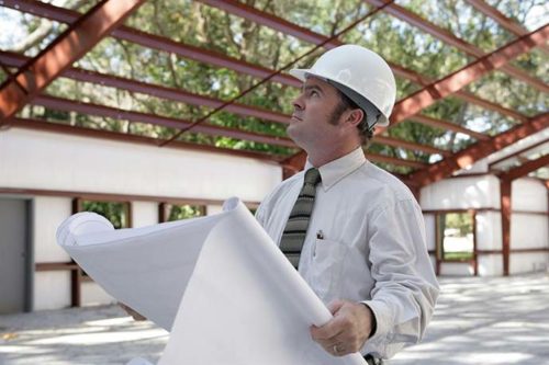 builder standing with a blueprint