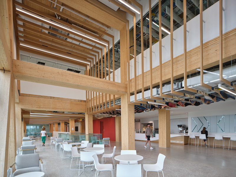 Modern interior with wooden beams, bright lighting, and casual seating areas; features a café in a vibrant, open space.