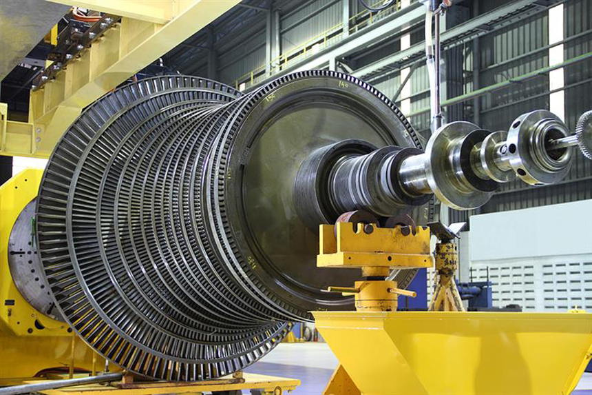 Large industrial turbine with multiple metal blades and complex rotating components in a maintenance facility.